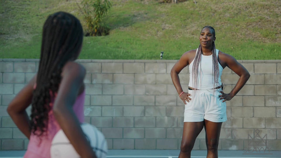 Reshanda Gray in pink box braids on an outdoor court with a young player