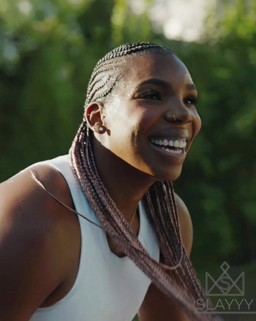 Reshanda Gray smiling on an outdoor court, pink box braids swinging