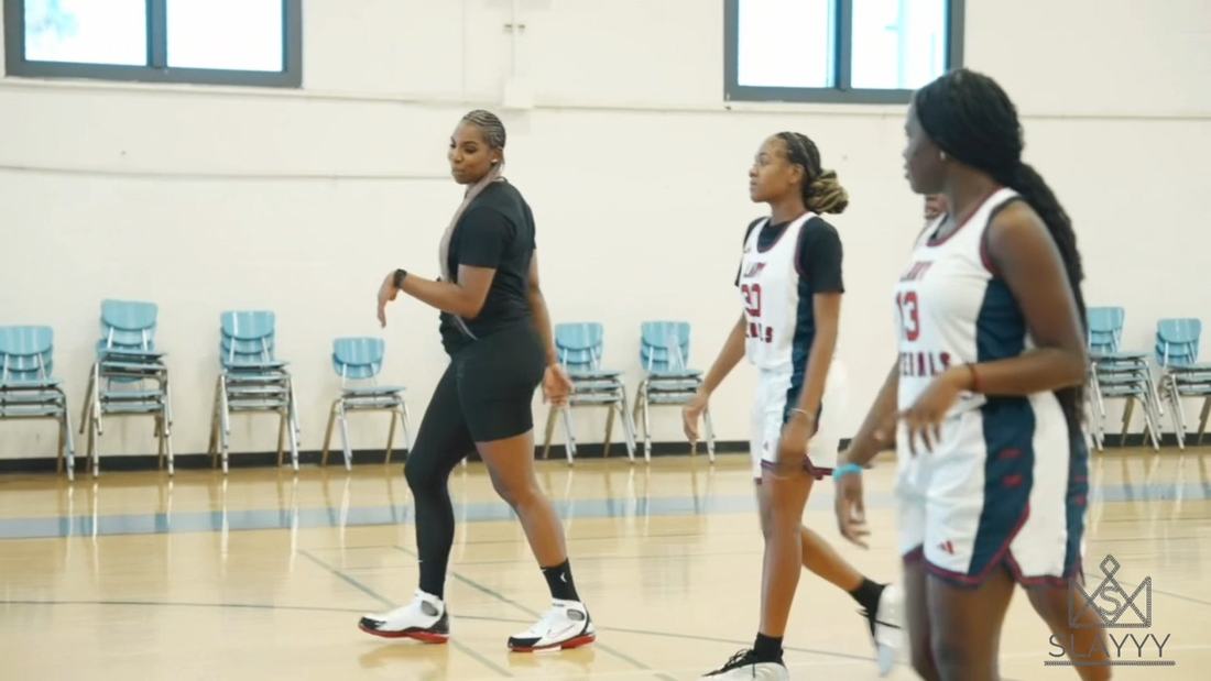 Reshanda Gray in long box braids walking the court with Lady Generals players