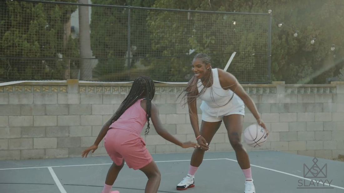 Reshanda Gray in pink box braids playing one on one with a young player outdoors