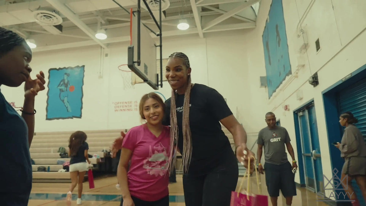 Reshanda Gray in pink box braids greeting young players in a gym
